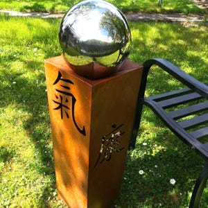 Columna de metal oxidado de Japón con bola y caracteres japoneses.