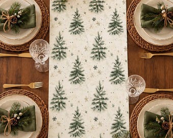 Puede incluir: Un camino de mesa blanco con un patrón repetitivo de pinos verdes y pequeños copos de nieve dorados. El camino está centrado en una mesa de madera con cuatro cubiertos, cada uno con un plato, una servilleta verde y cubiertos dorados.