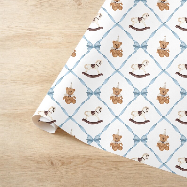 K&ouml;nnte beinhalten: Wei&szlig;es Geschenkpapier mit einem sich wiederholenden Muster aus Aquarell-Teddyb&auml;ren mit Partyh&uuml;ten und Schaukelpferden. Das Design ist in einem blauen Bandgitter mit Schleifen angeordnet. Das Papier ist teilweise gerollt.