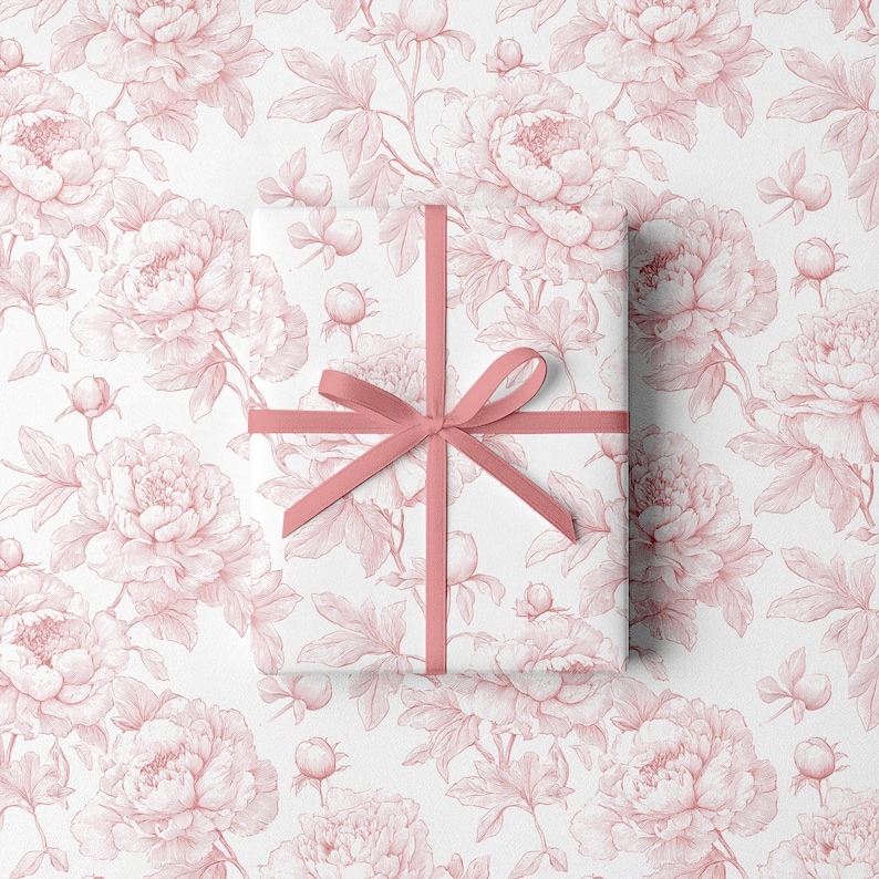 May include: A wrapped gift with a pink ribbon on a white background. The wrapping paper features a repeating pattern of pink peony flowers and leaves. The ribbon is tied in a bow.