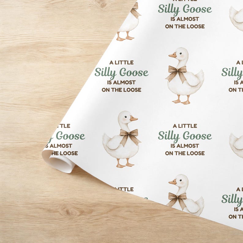 May include: White wrapping paper featuring a repeating pattern of watercolor geese with brown bows. The text "A Little Silly Goose Is Almost On The Loose" is printed in green. The paper is partially rolled.