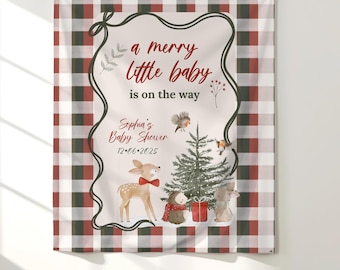 May include: A tapestry with a red, black, and white plaid pattern background. The center features a cream-coloured oval with the text "a merry little baby is on the way." Illustrations include a deer, birds, a Christmas tree, and woodland creatures.