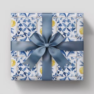 May include: A gift box wrapped in blue and white patterned paper with a blue bow. The paper features a repeating pattern of blue and white tiles with lemons.