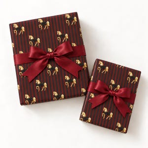 May include: Two rectangular gift boxes wrapped in dark red and black striped paper featuring a repeating pattern of gold horses with black bows. Each box is tied with a wide, smooth, deep red satin ribbon finished in a large, centered bow.