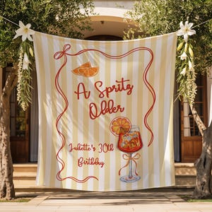 May include: A banner with vertical yellow and white stripes, adorned with the text "A Spritz Older" in red script, along with an illustration of a cocktail and orange slices. The banner also includes the text "Juliette's 30th Birthday".