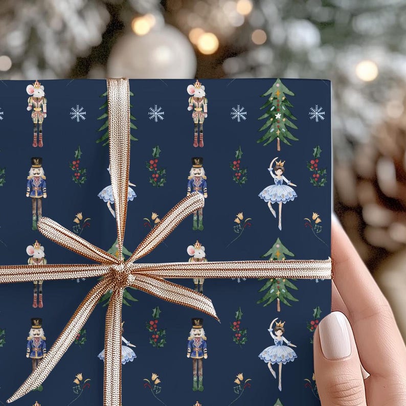 May include: Navy blue wrapping paper with a festive pattern of nutcrackers, mice, ballerinas, and Christmas trees. A gold ribbon is tied around the paper. The design is perfect for holiday gifts.