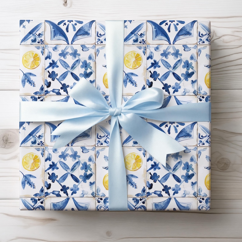 May include: A gift box wrapped in blue and white patterned paper with a light blue ribbon. The paper features a repeating pattern of lemons and blue and white tiles.