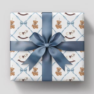 K&ouml;nnte beinhalten: Ein Geschenk, verpackt mit einem blauen Satinband und einer Schleife. Das Geschenkpapier zeigt ein sich wiederholendes Muster aus Teddyb&auml;ren, Schaukelpferden und blauen Schleifen auf wei&szlig;em Hintergrund. Perfekt f&uuml;r einen besonderen Anlass.