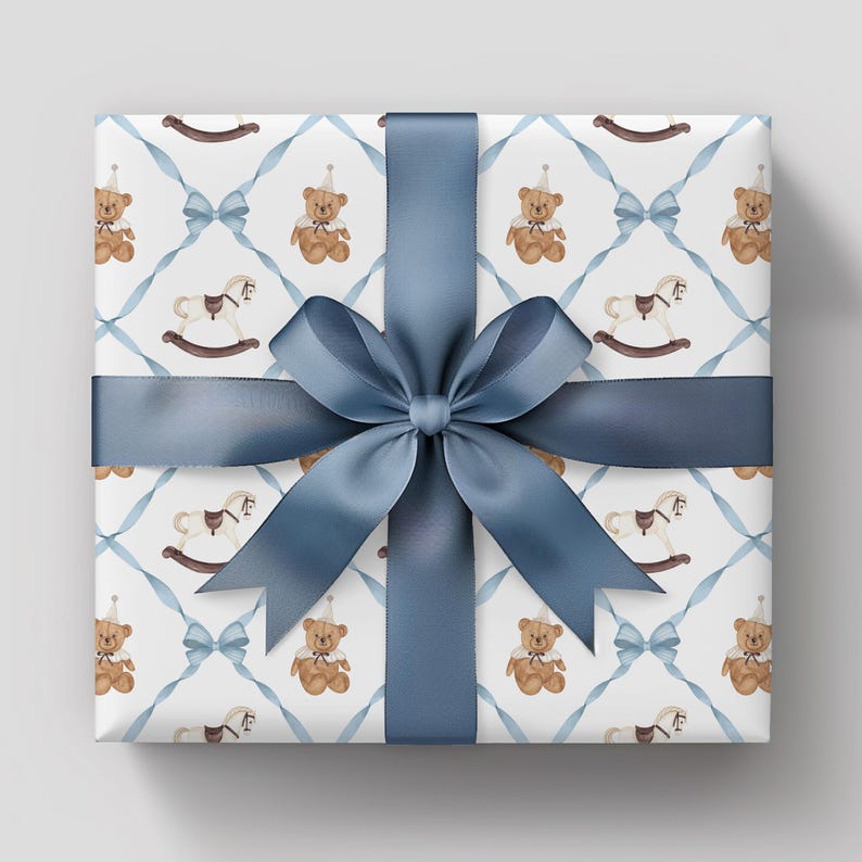 K&ouml;nnte beinhalten: Ein Geschenk, verpackt mit einem blauen Satinband und einer Schleife. Das Geschenkpapier zeigt ein sich wiederholendes Muster aus Teddyb&auml;ren, Schaukelpferden und blauen Schleifen auf wei&szlig;em Hintergrund. Perfekt f&uuml;r einen besonderen Anlass.