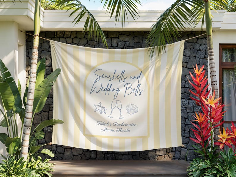 May include: A banner with vertical yellow and white stripes, featuring the text "Seashells and Wedding Bells" in a decorative font. The banner includes illustrations of a starfish, champagne flutes, and a seashell. The text "Taliah's Bachelorette Miami, Florida" is also present.