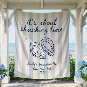May include: A striped banner with the text "It's about shucking time" and an illustration of two oysters. Below the illustration is "Emily's Bachelorette, Cape Cod, MA, 2026". The banner is blue and white and hangs in front of a beach scene.