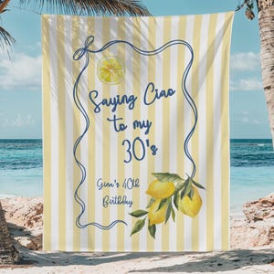 May include: Beach towel with a yellow and white striped background. The towel has a blue border with the text "Saying Ciao to my 30's" and "Gina's 40th Birthday". A lemon illustration is in the center and a lemon branch is at the bottom.