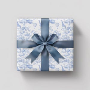 May include: A white gift box with a blue ribbon and a blue and white pattern of giraffes, elephants, and hot air balloons.