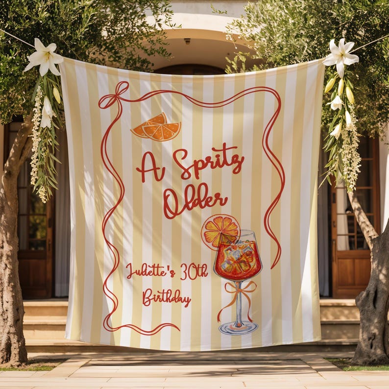 May include: A banner with a yellow and white striped background, featuring the text "A Spritz Older" in red script, along with an illustration of an orange slice and a cocktail. The text "Juliette's 30th Birthday" is also included.