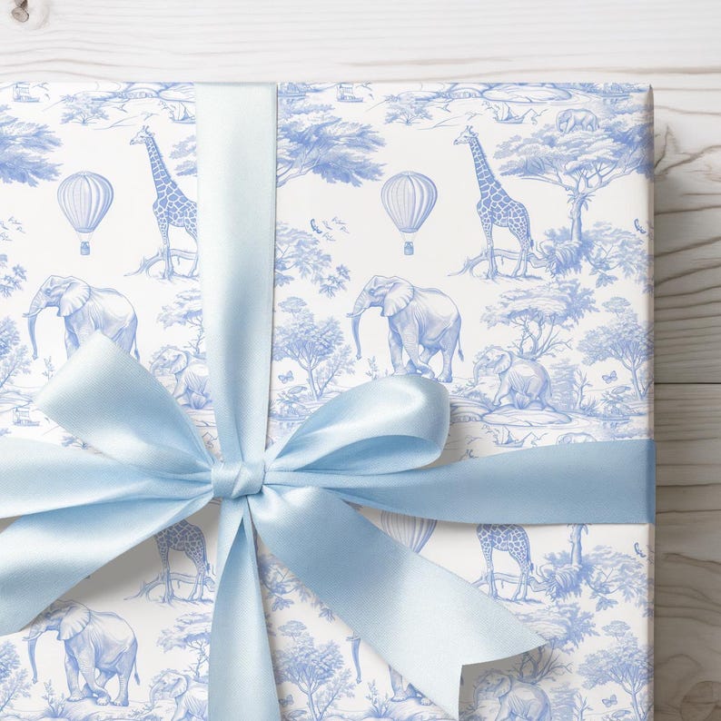May include: A blue and white gift wrap with a pattern of giraffes, elephants, and hot air balloons. The gift wrap is tied with a light blue ribbon.
