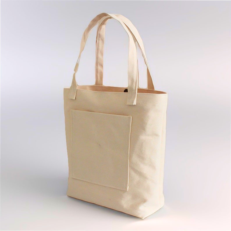 K&ouml;nnte beinhalten: Eine beige Canvas-Tragetasche mit einer gro&szlig;en Tasche auf der Vorderseite. Die Tasche hat zwei Henkel und ist aus robustem Material.