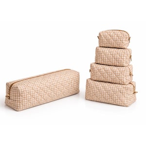 May include: A set of five beige and white gingham patterned cosmetic bags in various sizes. The bags are quilted and have gold-colored zippers. One long rectangular bag is separate from the stack of four smaller bags.