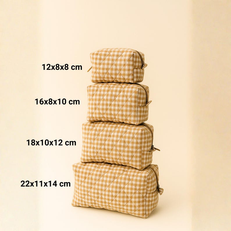 May include: Four stacked, quilted cosmetic bags in varying sizes. The bags feature a tan and white gingham pattern. Measurements are 12x8x8 cm, 16x8x10 cm, 18x10x12 cm, and 22x11x14 cm. Each bag has a zipper closure.