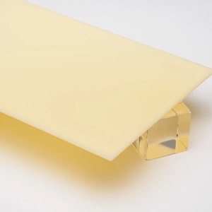 May include: A pale yellow acrylic sheet, slightly translucent, resting on a clear acrylic block.