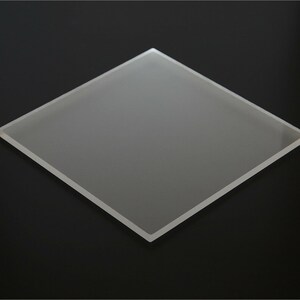 May include: A frosted glass square, approximately 10 inches by 10 inches, with a smooth, slightly textured surface.