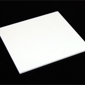 May include: A square, white foam board against a black background. The board is clean and appears to be unused. The edges are crisp and well-defined, suggesting a precise cut. The overall impression is of a simple, blank surface.