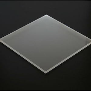 May include: A frosted glass square, approximately 10 inches by 10 inches, with a smooth, slightly textured surface.