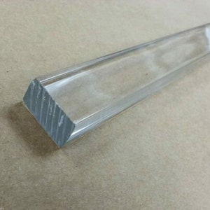 May include: Clear acrylic rod with a rectangular cross-section. The rod has a smooth, polished surface and is approximately 12 inches long.