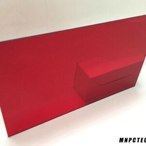May include: A red cardboard display stand with a cut-out slot for a product. The stand is designed to be folded and assembled.