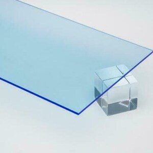 May include: A sheet of light blue acrylic plastic with a blue edge, resting on a clear glass block.