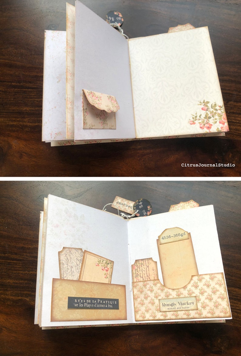 May include: An open journal with a floral design on the cover. The pages are decorated with vintage-style paper ephemera, including tags, labels, and pockets. The text on the page reads "REES DE LA PRATIQUE 'ur les Playıs d'armes &agrave; fru." and "Rungis Market March&eacute; pour Eleveur".