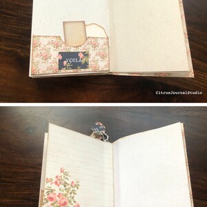 May include: Open vintage journal with a floral design on the cover. The journal has a pocket on the inside cover with a tag that says "VOILA". The pages are lined and blank.