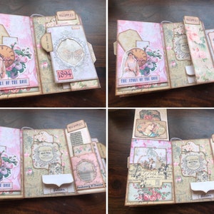 May include: A pink and brown scrapbook with a floral design and the text "The Story of the Rose" on the cover. The scrapbook has multiple pockets and flaps that can be opened and closed.