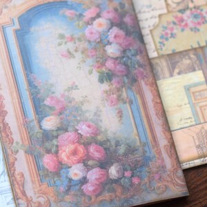 May include: A vintage-style journal cover with a floral design. The cover features a gold frame with a blue and white background and a bouquet of pink and white roses.