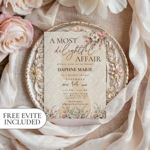 May include: A bridal shower invitation with the text "A Most Delightful Affair" and details for Daphne Marie's shower on May 14, 2026. The invitation features floral accents and is set on a decorative plate with a soft, neutral background.