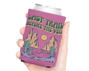 May include: Pink can cooler featuring a desert landscape design with the text "Last Trail Before The Veil".