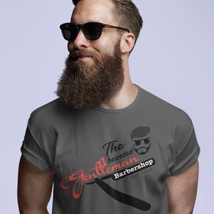 May include: A gray t-shirt with a red and black graphic design that says "The bearded Gentleman Barbershop Est. 1954".