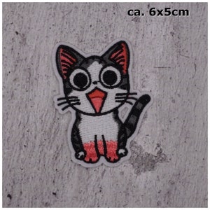 Könnte beinhalten: Gestickter Bügelaufkleber mit einem Cartoon-Katzenmotiv mit schwarz-weißem Fell, Brille und herausgestreckter rosa Zunge. Die Katze ist etwa 6 x 5 Zentimeter groß.