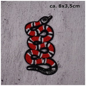 Könnte beinhalten: Gestickter Schlangen-Patch in Rot und Weiß, ca. 8 x 3,5 cm.