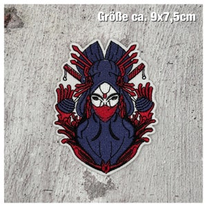 Könnte beinhalten: Gestickter Bügelaufkleber mit einer stilisierten Illustration einer Frau, die eine blaue Kapuzenmaske mit roten Akzenten trägt. Die Frau ist von roten Blumendesigns umgeben und hält zwei Schwerter. Der Patch ist etwa 9 x 7,5 Zentimeter groß.
