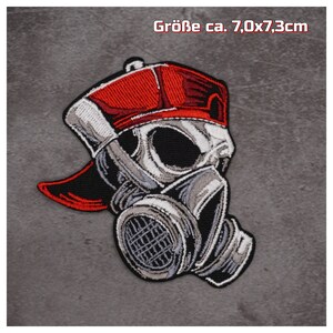 Könnte beinhalten: Gestickter Aufnäher mit einem Totenkopf, der eine rot-weiße Baseballkappe und eine Gasmaske trägt. Der Aufnäher ist ca. 7,0 cm x 7,3 cm groß.