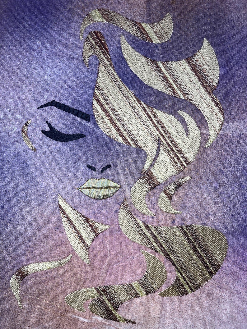 May include: A stylised embroidered image of a woman's face with a purple and pink background. The woman's hair is a gold and brown striped pattern.
