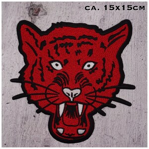 Könnte beinhalten: Roter gestickter Bügel-Patch mit dem Gesicht eines Tigers mit schwarzen Umrissen und weißen Zähnen. Der Patch ist etwa 15 cm x 15 cm groß.