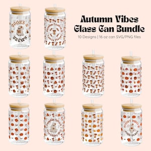 May include: A bundle of ten glass can designs with bamboo lids and straws. The clear glass cans feature autumn-themed graphics, including pumpkins, leaves, coffee cups, and ghosts. Text on the cans includes "Autumn Vibes," "Books & Brews," and "Pumpkin Spice Everything Nice." Each can holds 16 oz.