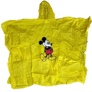 May include: Bright yellow hooded poncho featuring a Mickey Mouse graphic. The poncho is made of a lightweight, crinkled material. The Mickey Mouse graphic is in black, white, red, and yellow. The poncho is designed to be worn over clothing for rain protection.
