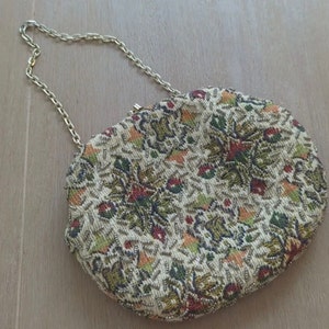 May include: A vintage beaded evening bag with a floral pattern in shades of green, red, and orange. The bag has a gold chain strap.