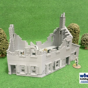 Puede incluir: Maqueta gris de un edificio dañado, con tejado y paredes parcialmente derrumbados. El modelo incluye ventanas con contraventanas y una chimenea. Árboles y soldados en miniatura se colocan alrededor del edificio, para un juego de guerra.