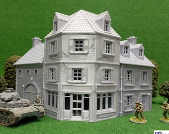 May include: A gray 3D printed model of a corner building with a garage door, windows, and a roof. The building is surrounded by green grass and miniature figures.