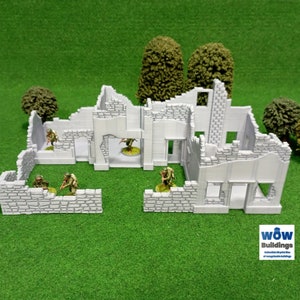 Puede incluir: Un modelo detallado de un edificio en ruinas, pintado en color gris claro, con pequeñas figuras verdes que representan soldados. El modelo está colocado sobre una superficie verde, con pequeños árboles verdes en el fondo. El texto "WOW Buildings" es visible en la esquina inferior derecha de la imagen.