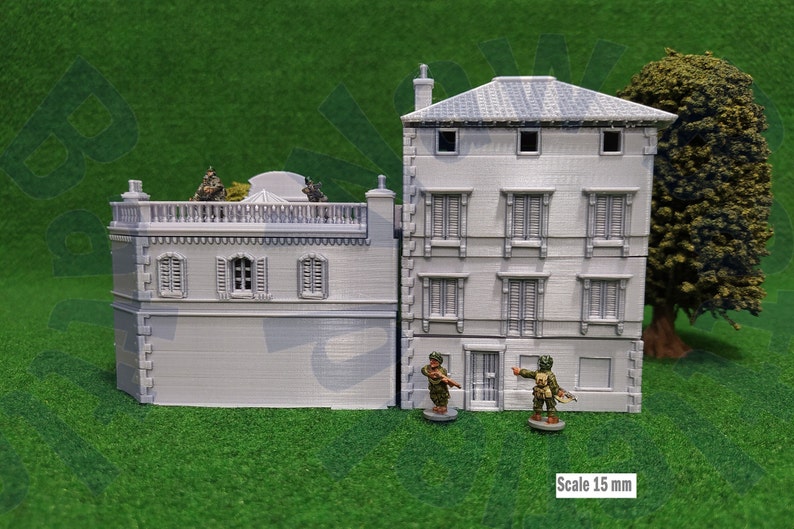Puede incluir: Maqueta gris de un edificio de dos pisos con ventanas detalladas y tejado de tejas. Dos figuras en miniatura est&aacute;n de pie frente al edificio. La escala es de 15 mm.