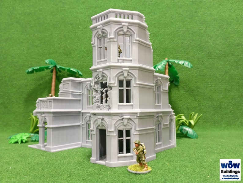 May include: A gray, detailed, multi-level, ruined building model with a small figure standing in front of it. The building has a tower with a window and a balcony. The building is on a green surface.